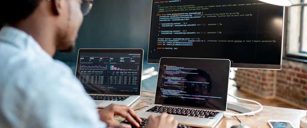 man programming on computer and two laptop