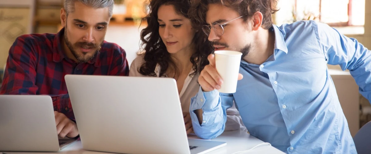 Group of people working at a table with a 2 laptop
